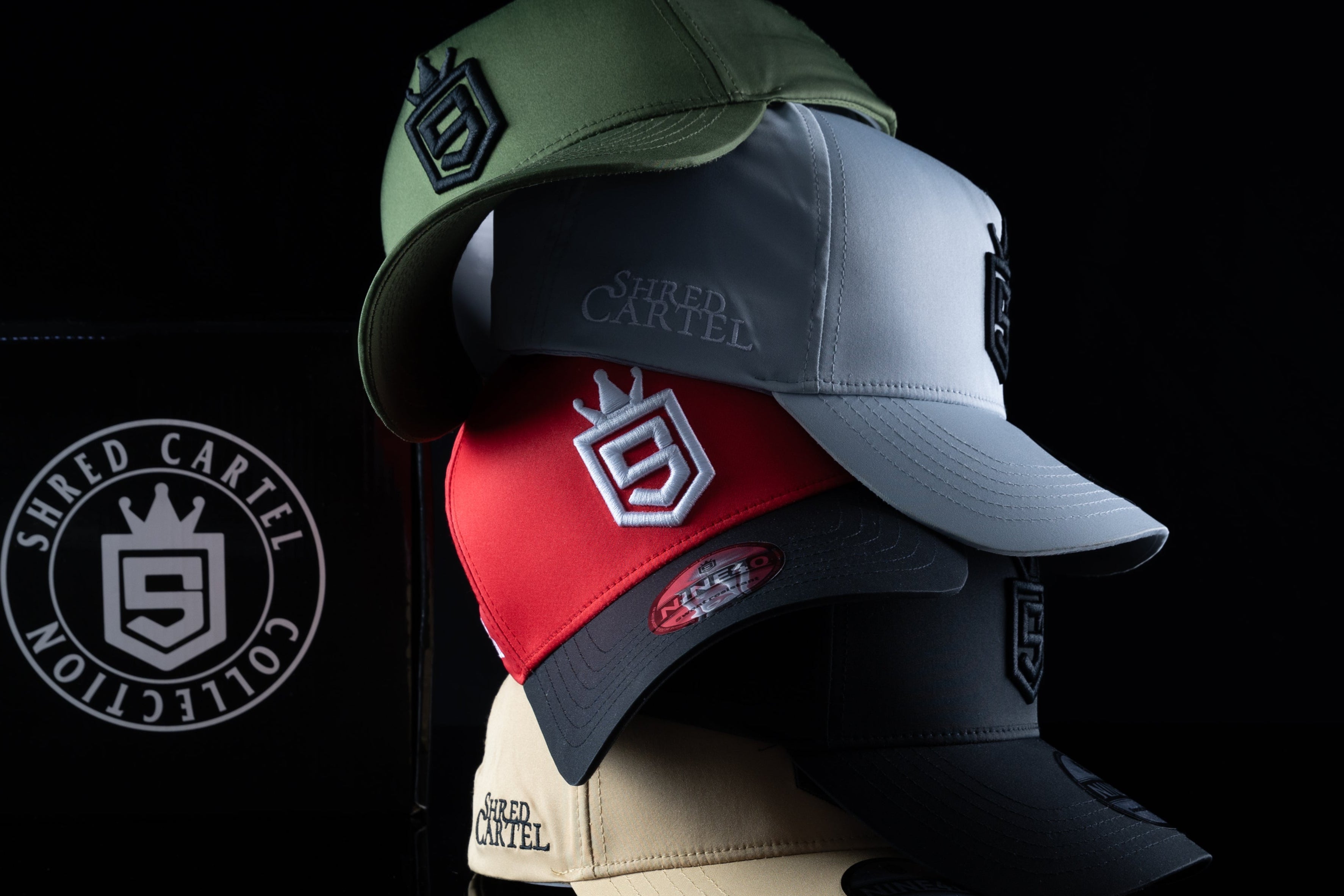 Four baseball caps in different colors with a brand logo on a black background